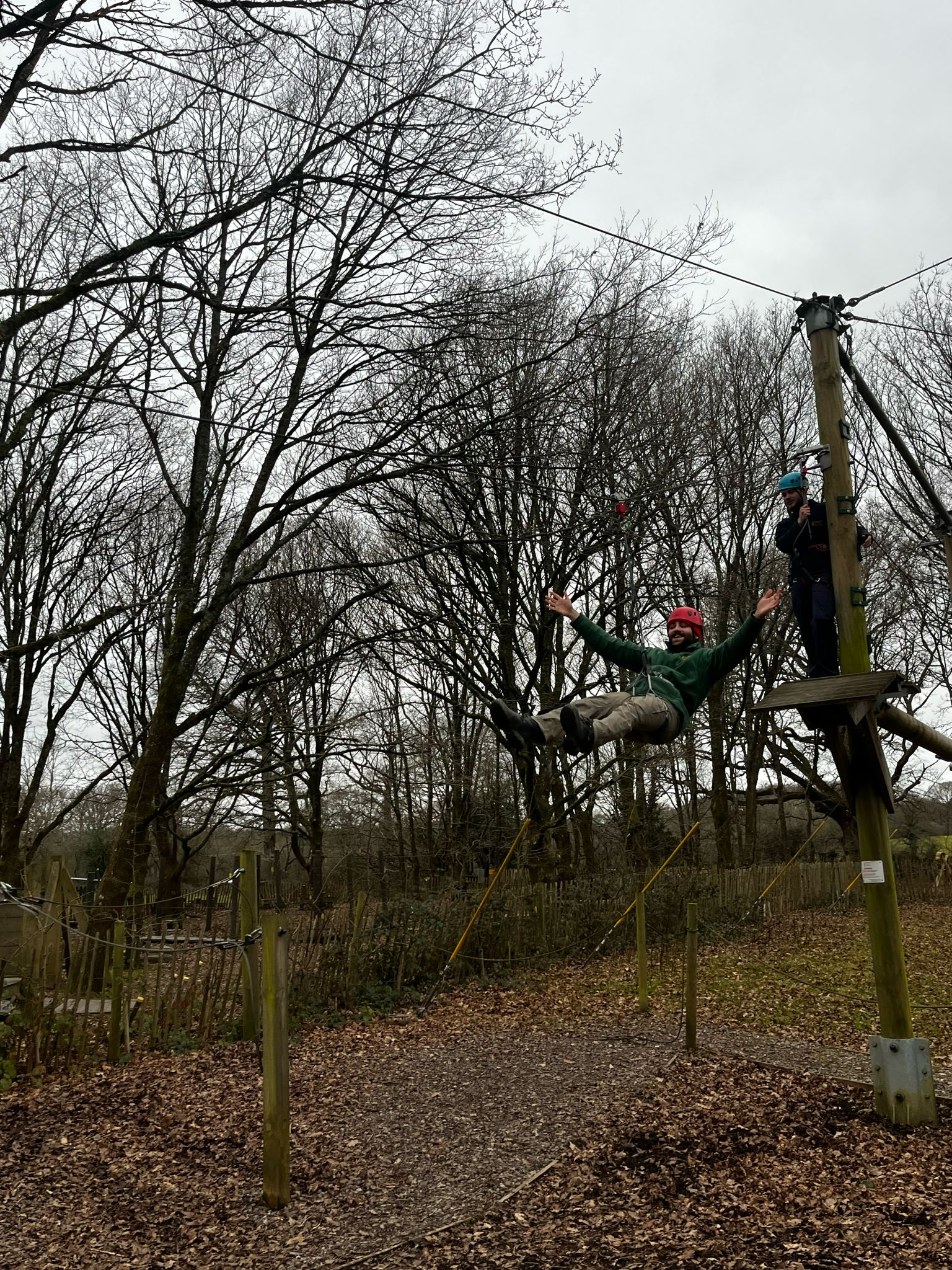 person sliding on a zipline surrounded by forest.